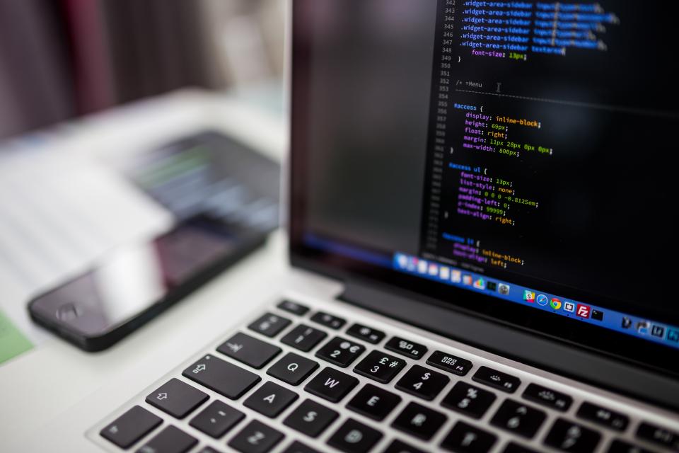 Ảnh kỹ sư ngồi trước laptop đang hiển thị mã nguồn trong văn phòng, gợi không khí làm việc với dữ liệu web và hệ thống tự động.